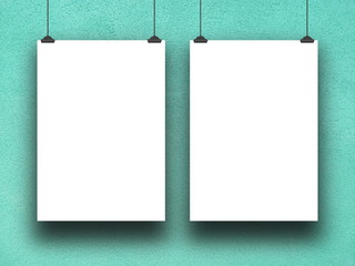 Close-up of two blank square frames hanged by clips against aqua rough plaster wall background