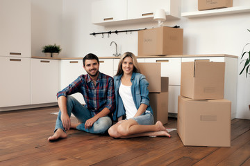 Happy couple with unpacked boxes in kitchen