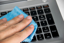 Close Up Holding Blue Wipes To Clean On Keyboard Laptop