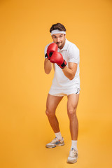 Poster - Concentrated young man boxer in red gloves ready to fight