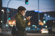 © Eugenio Marongiu - Half length of young handsome caucasian brown straight hair woman holding a smartphone looking down the screen in city night, face illuminated by screenlight - technology, communication concept