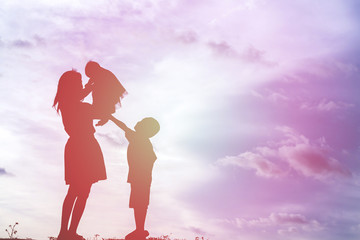 Wall Mural - Mother holding baby walking on the sunset background.