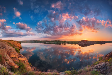 Wall Mural - Beautiful panoramic landscape with colorful cloudy sky, lake and mountains. Summer sunset at the river with clouds reflected in water. Panorama. Nature background