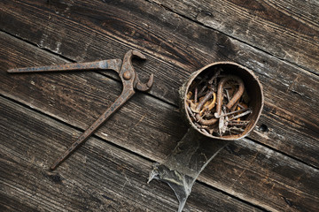 Wall Mural - old rusty pinchers with can of nails on wooden boards background