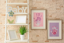 Family Hand Prints In Frame Hanging On Brick Wall