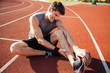 © Drobot Dean - Young male runner suffering from leg cramp on the track