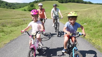 Wall Mural - Happy family riding bikes in mountain road