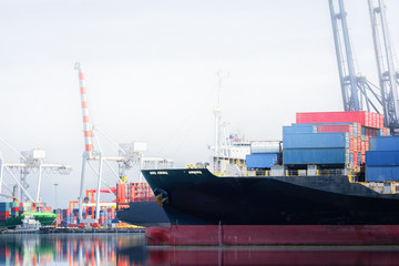 Logistics and transportation of International Container Cargo ship in a harbor with water reflections for logistic import export background and transport industry.