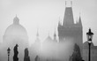 Detail of the Charles Bridge with statues and tower covered by mist.