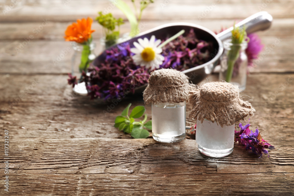 Composition with healing flowers and small glass bottles on wooden background