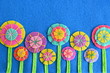 A row of colorful flowers on blue felt. Home bright flowers made of felt circles. Background for greeting card for birthday, Valentine's day, Easter, mother's day. Top view with copy space