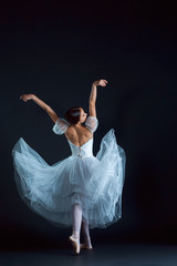 Wall Mural - Portrait of the classical ballerina in white dress on black background