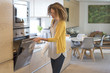 © onoky - Young woman opening door of an oven