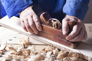 Carpenter working with plane on wooden background at Building Site. Joiner workplace