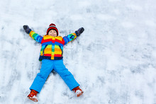 Little Kid Boy Making Snow Angel In Winter, Outdoors