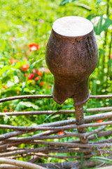 Canvas Print - broken clay pot close up at wattle fence