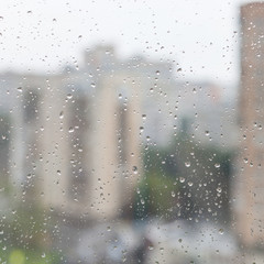 Poster - rain drops on window glass and blurred urban house