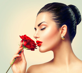 Wall Mural - fashion brunette model girl face portrait with red rose in her hand