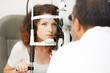 © Stocked House Studio - Pretty woman is looking into eye test machine with concentration in oculist lab