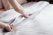 © sek_gt - Close up woman hand set up white bed sheet in hotel room