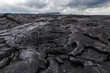 Bizarre formations on the lava fields of Puu Oo, Big Island Hawaii. The shiny rock consists of very fresh lava. The cone of Puu Oo is visible in the background.
