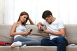 © perfectlab - Man and  young woman sitting on a couch and holding smartphones in their hands.