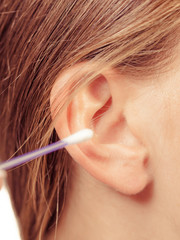 Wall Mural - Woman cleaning ear with cotton swabs closeup