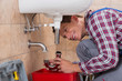 © Andrey Popov - Plumber Installing Sink Pipe In Bathroom