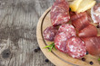 Dettaglio di tagliere con affettati tradizionali italiani: salame, bresaola, lardo e formaggio isolato su sfondo rustico