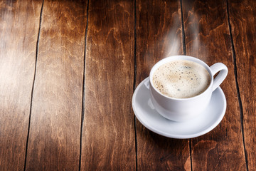 Wall Mural - white mug of coffee on a wooden background