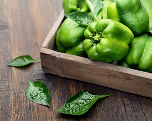 green bell peppers in a box on a wooden background