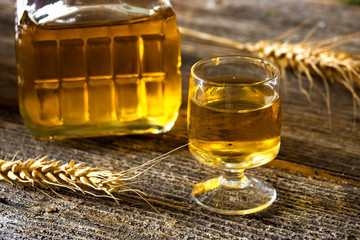 Glass of brandy or cognac and bottle on  wooden table.