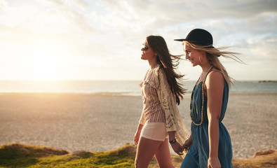 Two friends walking on the beach on a summer day