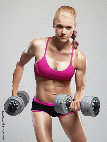 Fototapeta do kuchni fitness athletic woman pumping up muscles with dumbbells.beautiful blond girl in gym