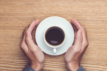 Male hands holding cups of coffee on rustic wooden table backgro