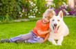 © Ermolaev Alexandr - kid and White Swiss Shepherd dog together on green grass