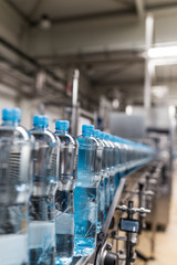 Wall Mural - Water factory - Water bottling line for processing and bottling pure spring water into small bottles. Selective focus.