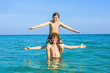 © travelview - boys having fun playing Piggyback in the warm ocean