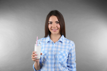 Poster - Attractive woman holding bottle with milk on grey background