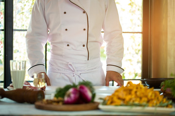 Man in uniform of chef. Guy standing at the table. He's a cook by education. Work to feed the others.