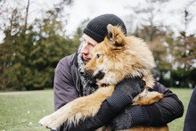 Man Hugging Dog In Park