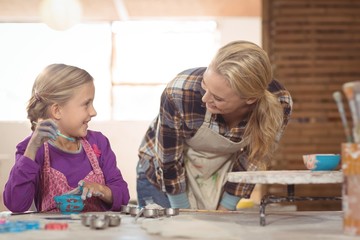 Female potter assisting girl in painting