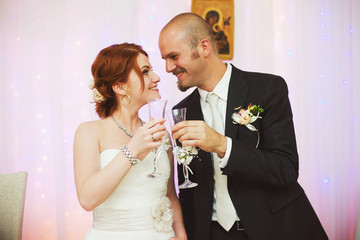 Wall Mural - Groom and bride cland glasses standing in the restaurant hall