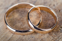 Two Gold Wedding Rings On Wooden Background
