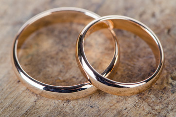 Two gold wedding rings on wooden background