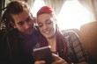 © Wavebreak Media - Smiling hipster couple using mobile phone
