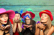 Frauen mit Hüte pusten bunte Federn aus den Händen - Spaß mit der Fotobox 