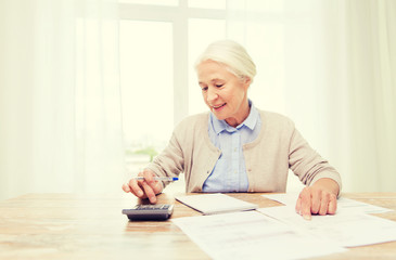 Poster - senior woman with papers and calculator at home