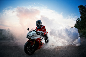 biker staying on bike  road with smoke of the tire, burn out in the moto show.  the Sunset