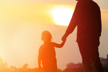 Silhouette Of Father And Daughter Holding Hands At Sunset